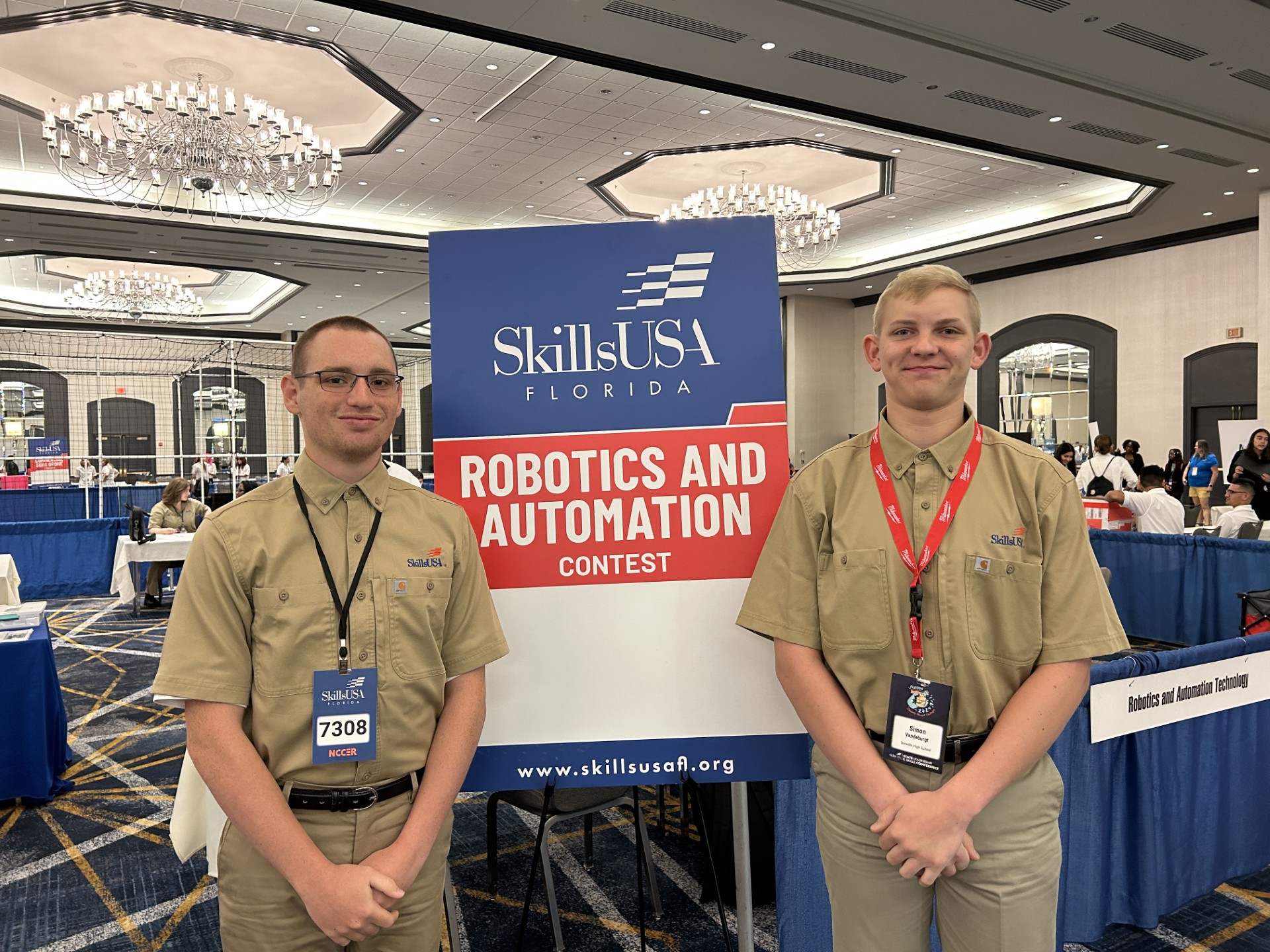 Two men in uniform standing in front of a signDescription automatically generated